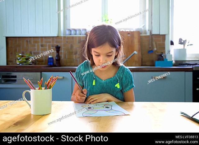 Little girl sitting at kitchen table, drawing an Easter bunny