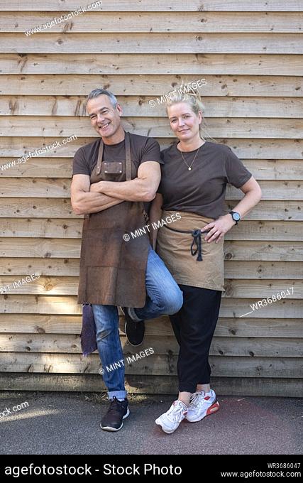 Man and woman in aprons, colleagues taking a break from work, laughing