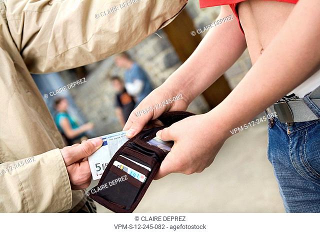 Mid section view of a teenage boy snatching Euro dollars from a wallet