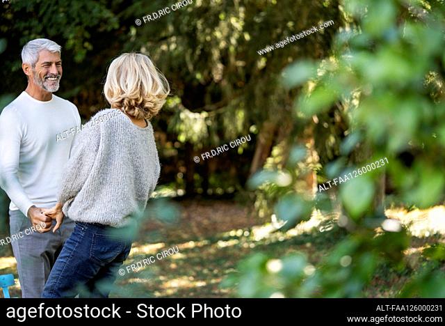 Smiling mature couple with holding hands looking at each other in backyard