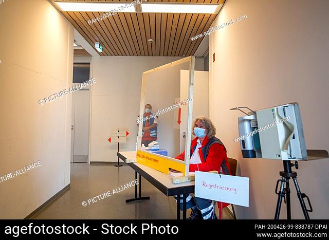 26 April 2020, Baden-Wuerttemberg, Neuenburg: An employee of the German Red Cross (DRK) is sitting at a table to register evacuees possibly infected with the...