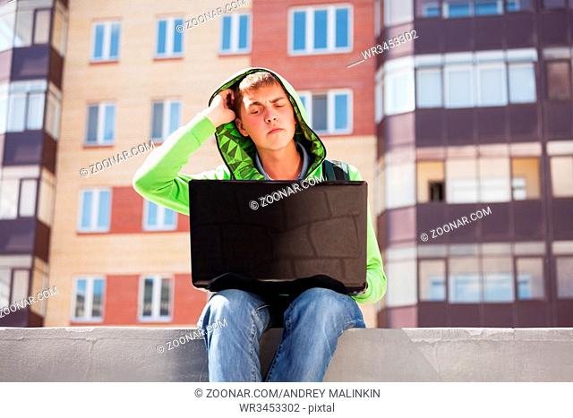 Young man using laptop on city street