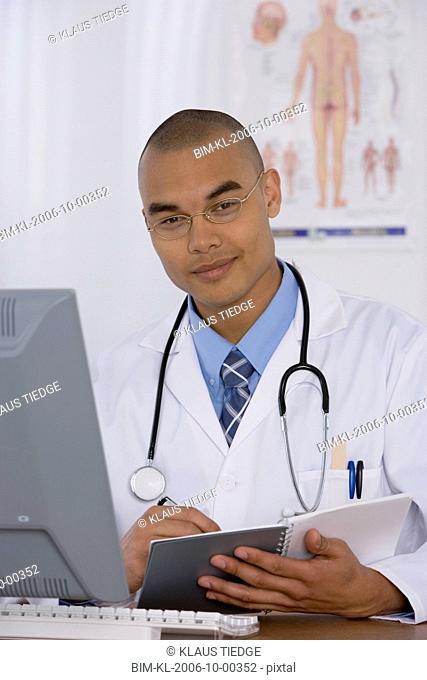 Male doctor writing in notebook