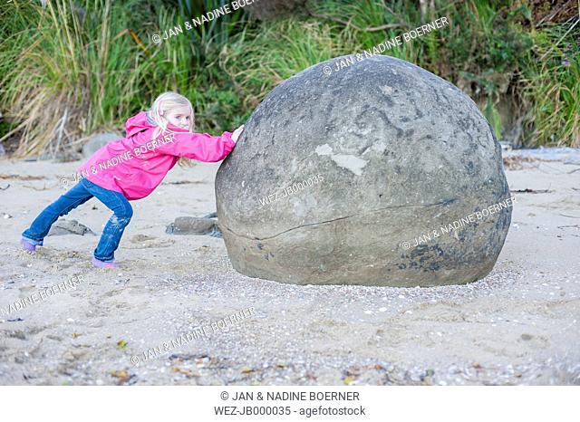New Zealand, North Island, Northland, Hokianga Harbour, girl pretending to push Kouto Boulder