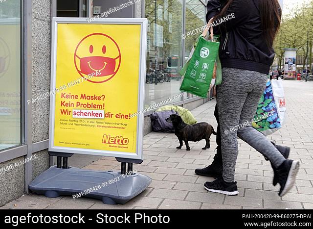 27 April 2020, Hamburg: On a display in front of a branch of the discounter Netto it is announced that masks will be given away as a gift if required at the...