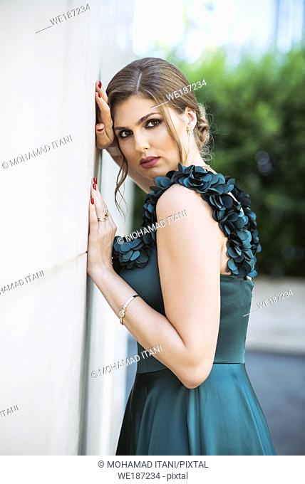 Beautiful woman leaning against wall outdoors
