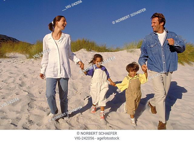 beach-scene, full-figure, family with two 4-6-year-old children walk laughing hand-in-hand down the dunes  - GERMANY, 11/09/2004