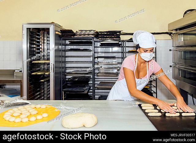 Woman rolling pastry dough on table in bakery