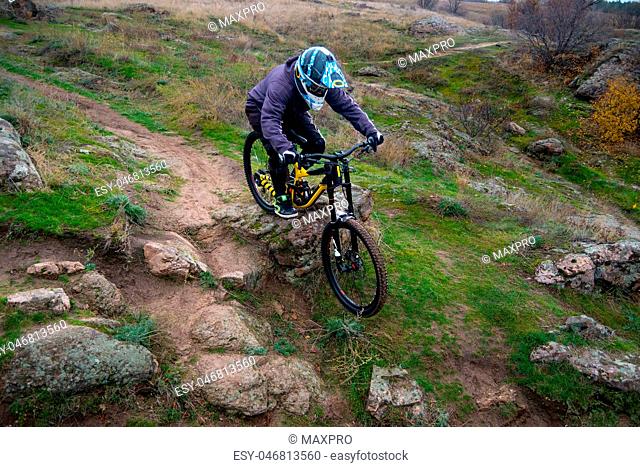 Professional Cyclist Riding Mountain Bike Down the Rocky Hill. Extreme Sport and Enduro Biking Concept