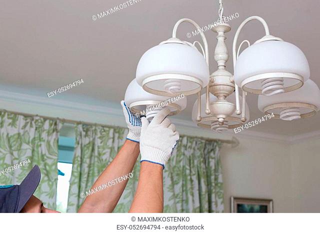 Man changes an electric light bulb, energy efficiency
