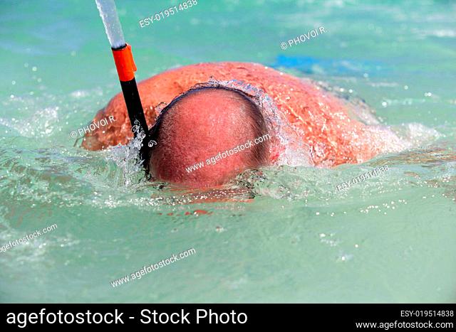 Old man bathing in the sea with mask and snorkel diving