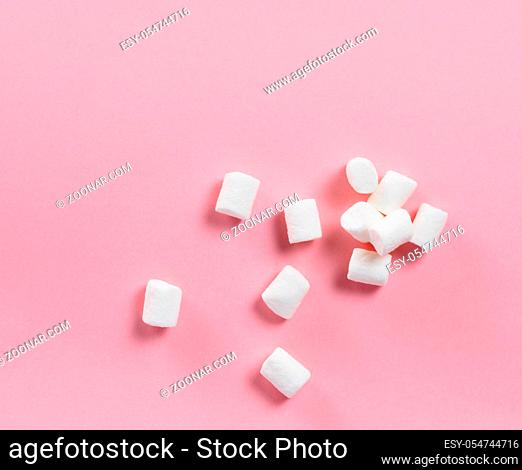 Marshmallows on pink background with copyspace. Flat lay or top view. Background or texture of colorful mini marshmallows