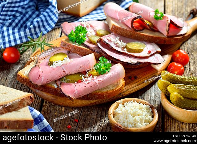 Brotzeit mit deftigem schwarzgeräucherten Landschinken und frischem Meerrettich auf Bauernbrot ? Bavarian snack with smoked country ham with freshly grated...