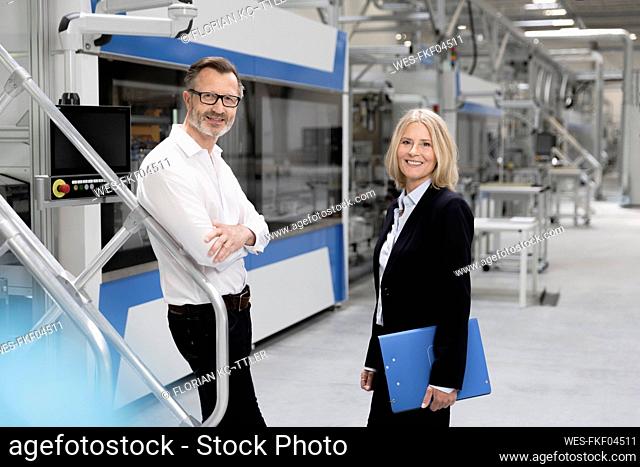 Male and female professionals standing together in factory