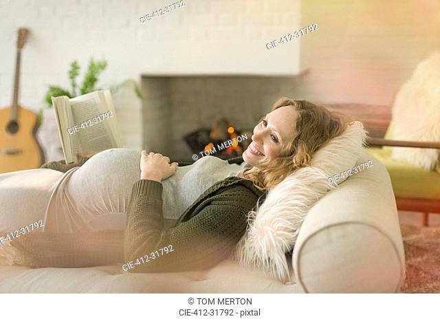 Smiling pregnant woman laying relaxing reading book