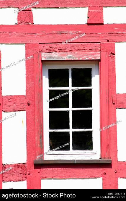 Timbered wall with red-colored wooden beams and white lattice windows