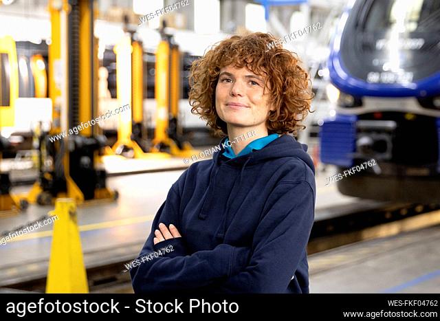 Confident engineer with arms crossed standing in warehouse at factory