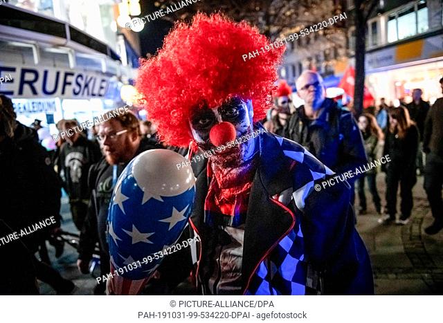 31 October 2019, North Rhine-Westphalia, Essen: A man disguised as a zombie clown is wandering through downtown Essen. The ""Zombie Walk""