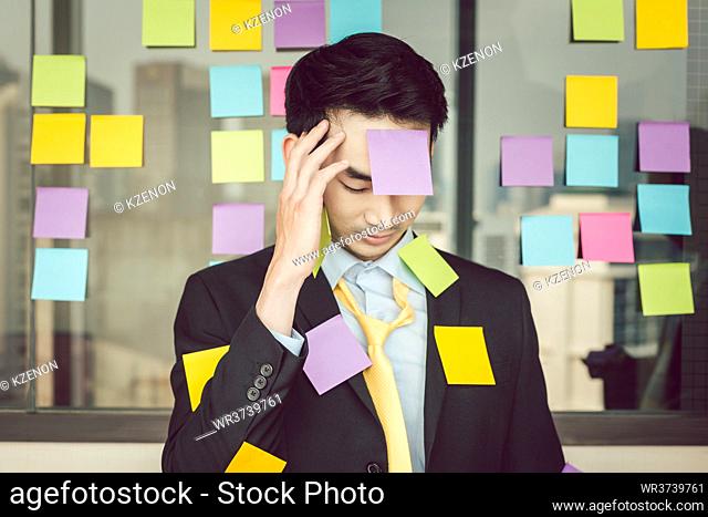 Portrait of young businessman looking at colorful sticky notes over his clothes