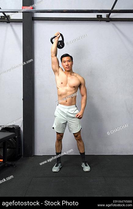 Fit man showcasing his strength at the gym while lifting a kettlebell