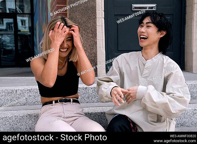 Young friends laughing together sitting on steps