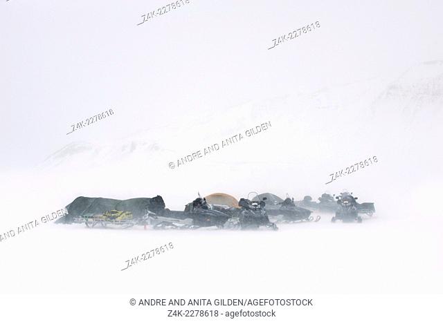 Basecamp with tents and snowmobiles in snowblizzard, Spitsbergen (Svalbard)