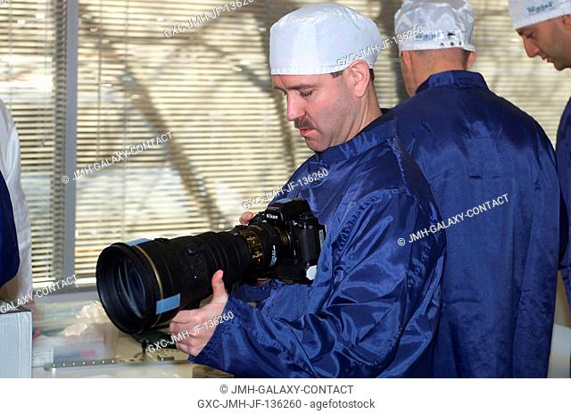 Astronaut John M. Grunsfeld, STS-109 payload commander, inspects still camera equipment during a crew equipment bench review in an offsite facility near Johnson...