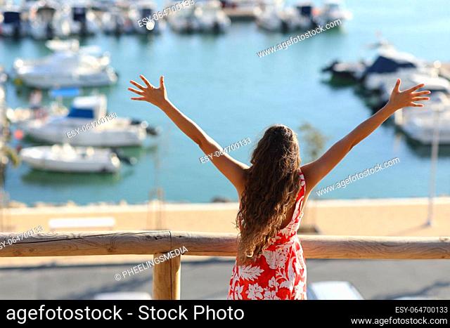 Back view portrait of a happy woman celebrating summer in a port