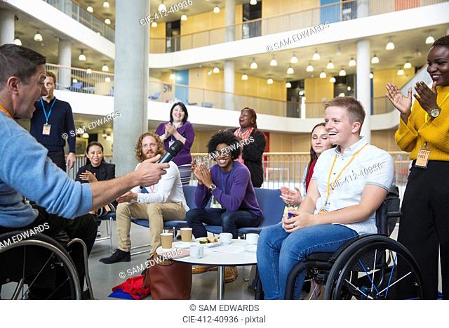 Colleagues clapping for speaker in wheelchair at conference