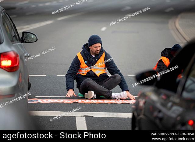 22 February 2023, North Rhine-Westphalia, Dortmund: A climate activist from the group Last Generation sits on the asphalt to block a major road