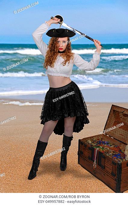 Beautiful young woman pirate opening a treasure chest