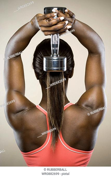 Rear view of a young woman exercising with a dumbbell