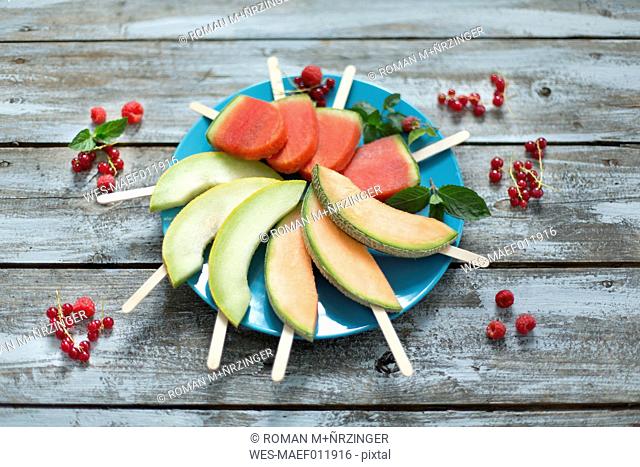 Plate of homemade watermelon ice lollies, slices of Galia and Cantaloupe melon