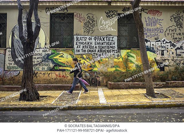A man walks past a house that is covered with graffitis in the Exarchia quarter in Athens, Greece, 19 November 2017. The lettering 'total resistance against the...