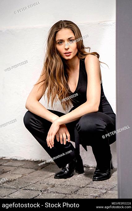 Beautiful woman crouching in front of white wall