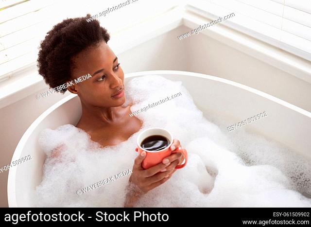 Woman with coffee cup in a bathtub