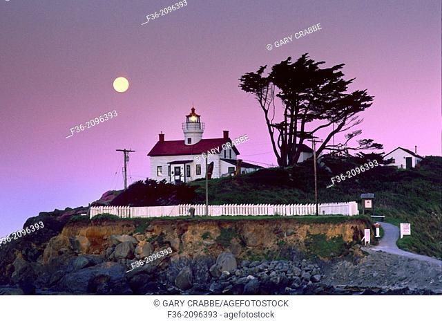 Full moon setting at dawn over Battery Point Lighthouse, Crescent City, Del Norte County, California
