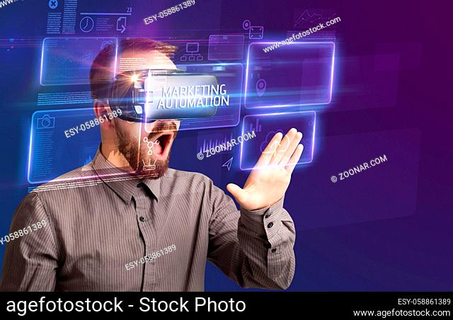 Businessman looking through Virtual Reality glasses with MARKETING AUTOMATION inscription, new technology concept