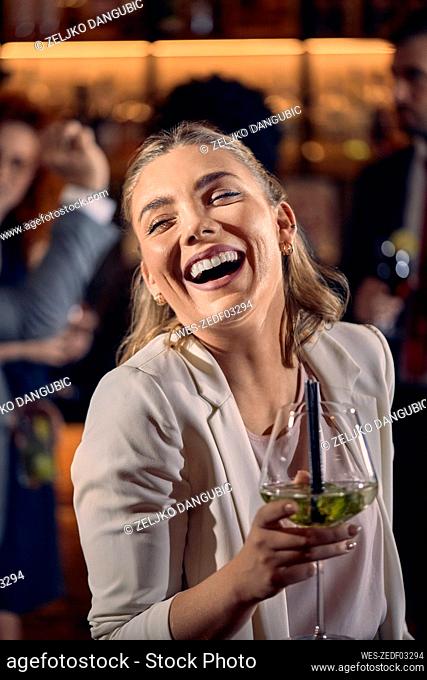 Portrait of a happy young woman having a cocktail in a bar