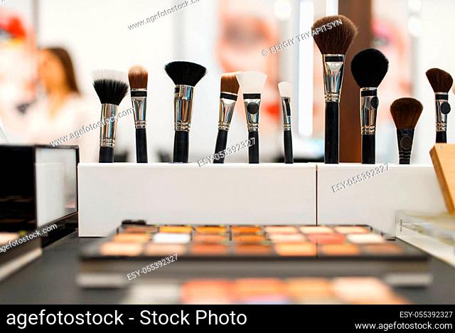 Shelf with shadows and brushes in cosmetics store, nobody. Luxury beauty shop, showcase with products in fashion market