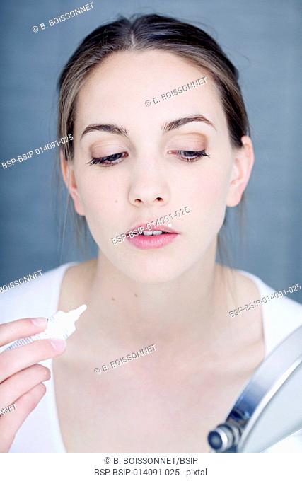 Woman applying cream to treat labial herpes
