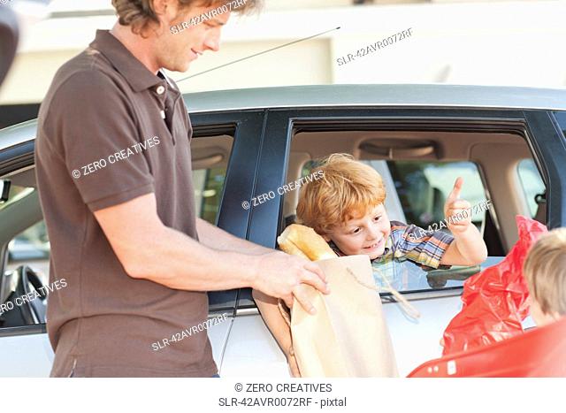 Father and sons loading groceries in car