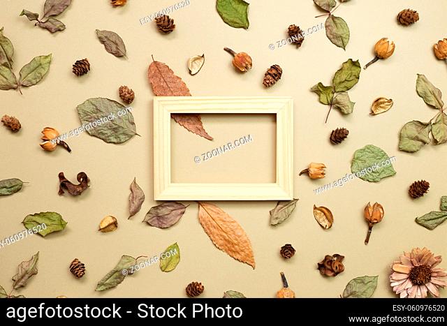 Wooden photo frame with autumn dry leaves on khaki brown background. flat lay, top view, copy space