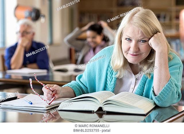 Confused older woman reading book in library