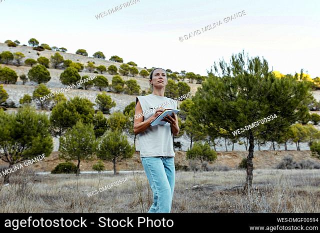 Female scientist contemplating while holding book at old mine