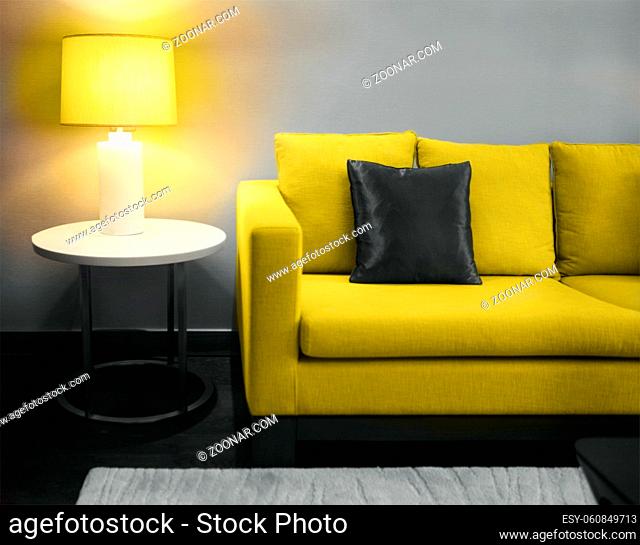 Cozy beautiful living room with illuminating yellow sofa and lamp with copy space. Toned image