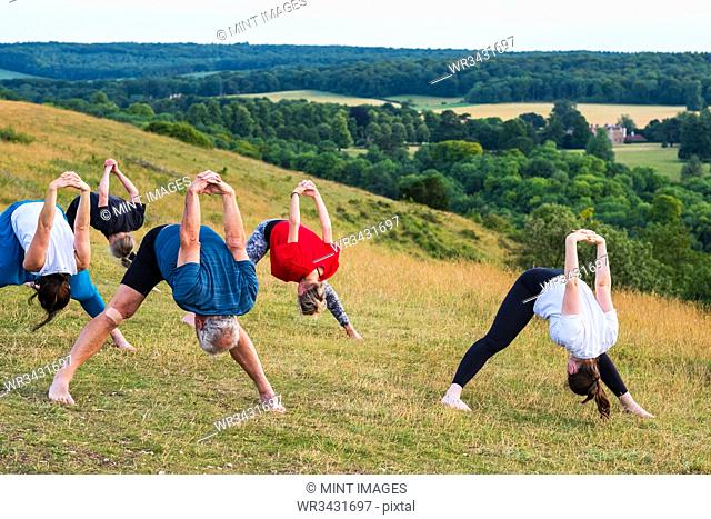 Group of women and men taking part in a yoga class on a hillside