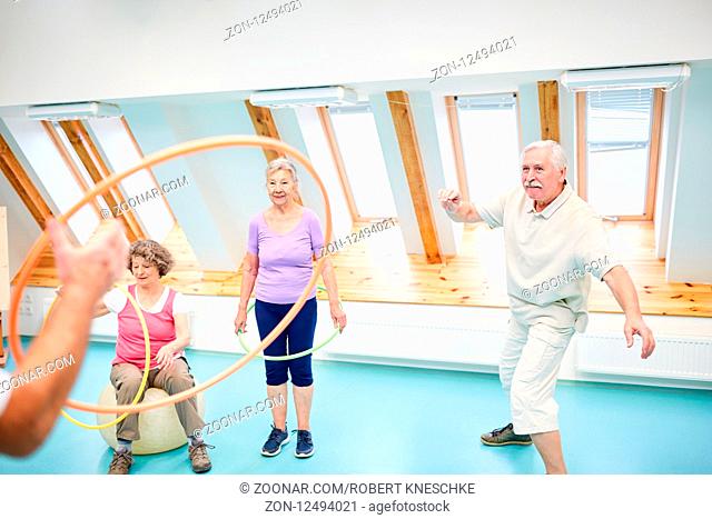 Vitale Senioren werfen mit Reifen im Fitnesscenter und spielen und haben Spaß