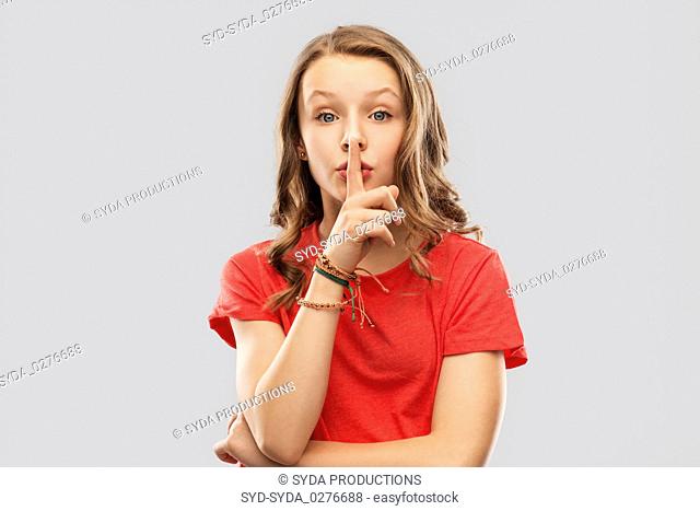 teenage girl in red t-shirt with finger on lips
