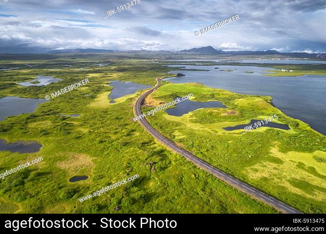Aerial view of road through green landscape with volcanic crater, pseudo-crater at Lake Mývatn, Skútustaðir, Norðurland eystra, Iceland, Europe